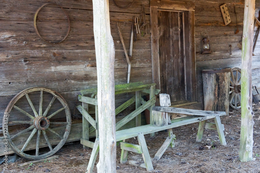Wooden bench and wheel on the front porch of an old log house in ...