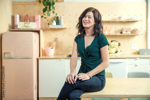 Portrait of a woman looking off camera while sitting on kitchen table., Studio City, CA, USA photo