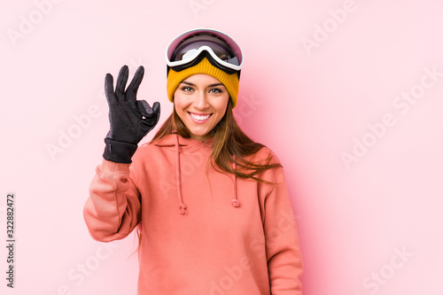 Young caucasian woman wearing a ski clothes isolated cheerful and confident showing ok gesture.
