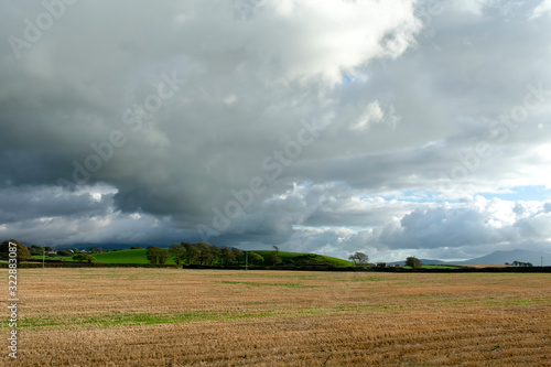 Landscape in rural north Wales, near Caernarfon. Cloudy storm clouds over farmers fields, with woods on the horizon. Countryside scene - copy space.