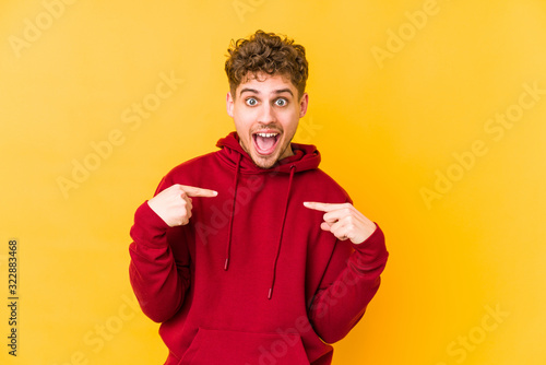 Photos surprised pointing with finger, smiling broadly.