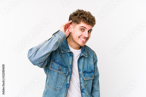 Young blond curly hair caucasian man isolated trying to listening a gossip. © Asier