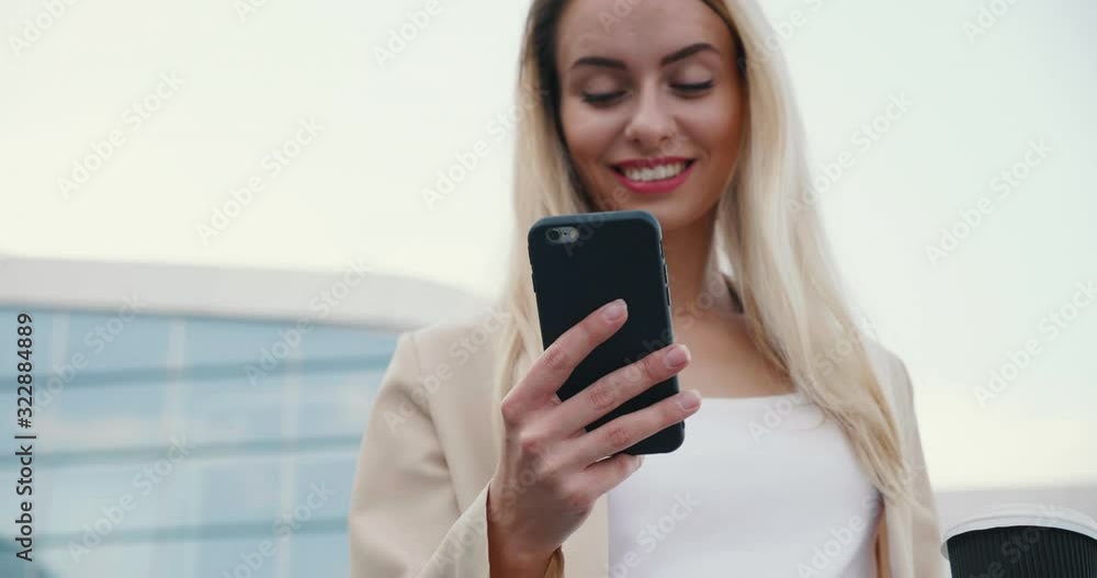 Close up Portrait of Attractive Young Woman standing with Cup of Coffee and Mobile Phone. Looking at Screen while reading Messages. Having good Mood and Attractive Appearance Close up Portrait of Attractive Young Woman standing with Cup of Coffee and Mobile Phone. Looking at Screen while reading Messages. Having good Mood and Attractive Appearance