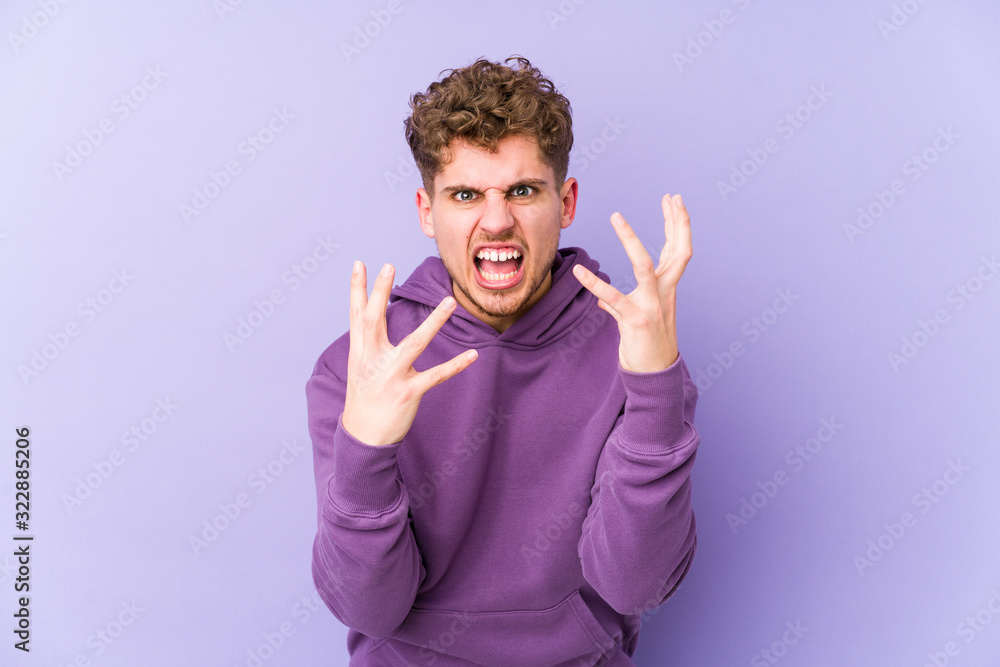 Young blond curly hair caucasian man isolated upset screaming with tense hands. Young blond curly hair caucasian man isolated upset screaming with tense hands.