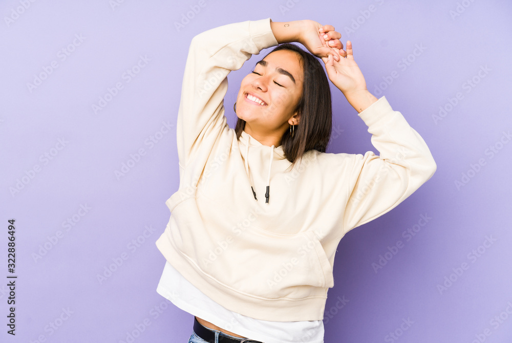 Young woman isolated on a purple background stretching arms, relaxed position. Young woman isolated on a purple background stretching arms, relaxed position.