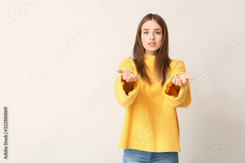 Hesitating young woman on light background. Concept of choice