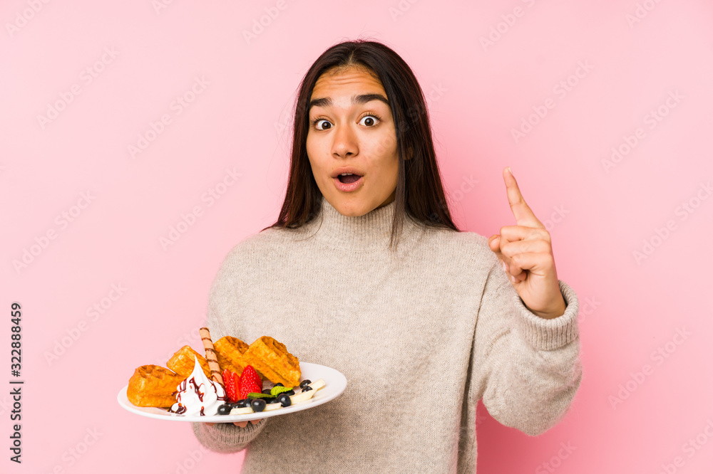 Young asian woman holding a waffle isolated having an idea, inspiration concept. Young asian woman holding a waffle isolated having an idea, inspiration concept.