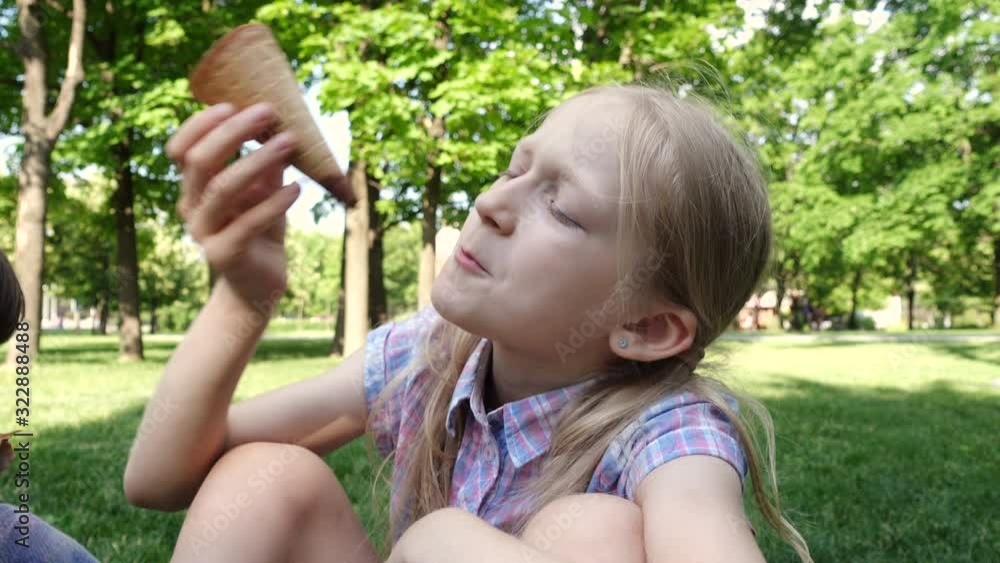 little girls eating ive cream sitting on a green lawn on a sunny summer day little girls eating ive cream sitting on a green lawn on a sunny summer day