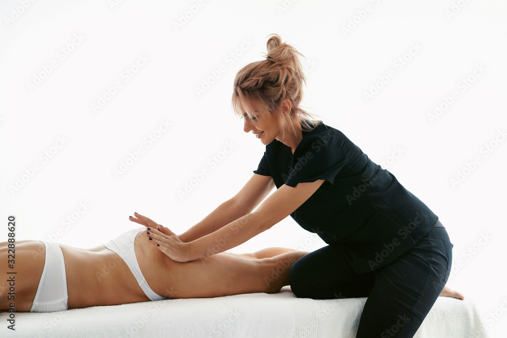 Obraz premium Fat burning massage. masseur making anti cellulite massage for young woman in wellness center or beauty salon. Perfect skin beauty concept