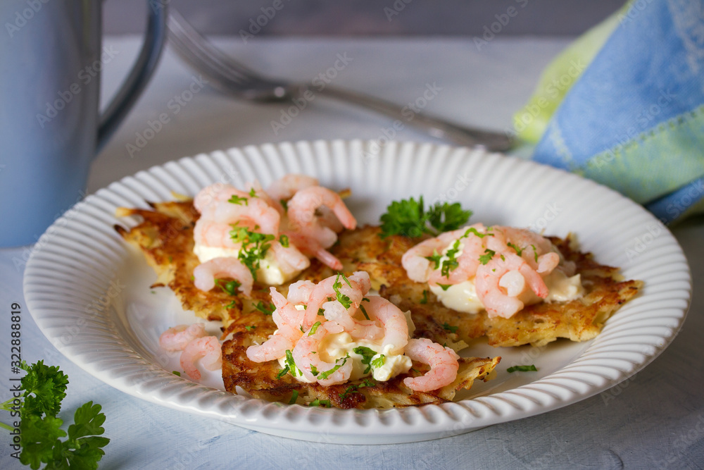 Potato cakes with topping: cream cheese and shrimps on white plate. Vegetable fritters, pancakes. Horizontal image Potato cakes with topping: cream cheese and shrimps on white plate. Vegetable fritters, pancakes. Horizontal image