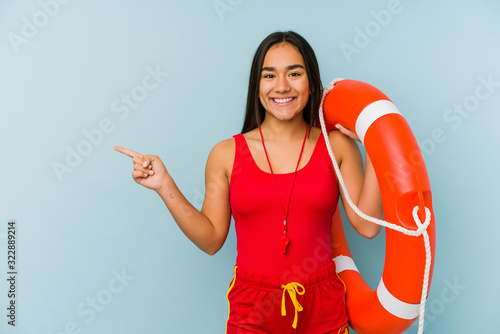 Young asian lifeguard woman isolated smiling and pointing aside, showing something at blank space.