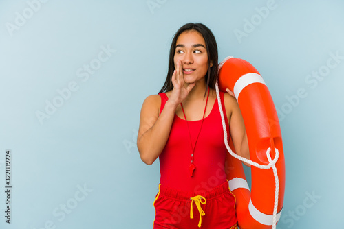 Young asian lifeguard woman isolated is saying a secret hot braking news and looking aside