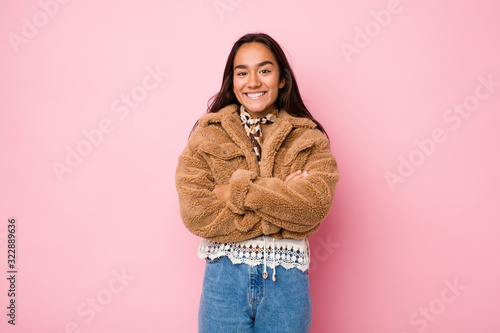 Young mixed race indian woman wearing a short sheepskin coatwho feels confident, crossing arms with determination. © Asier
