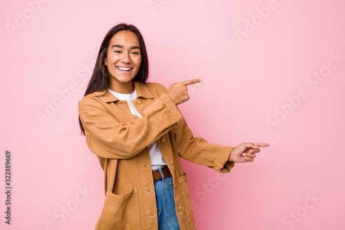 Young mixed race indian woman isolated excited pointing with forefingers away. © Asier