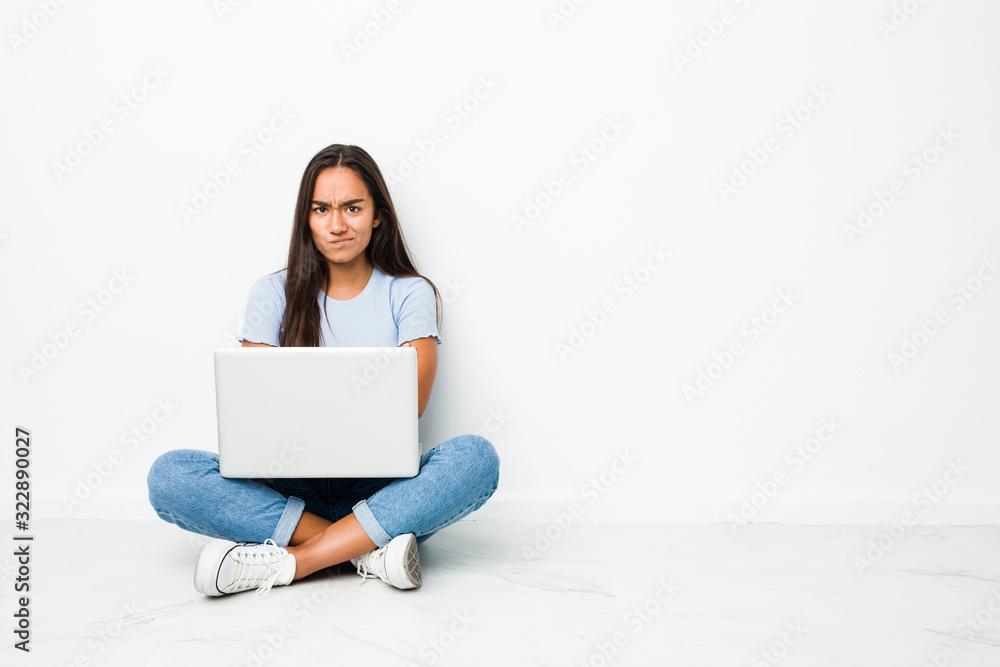 Young mixed race indian woman sitting working on laptop frowning face in displeasure, keeps arms folded. Young mixed race indian woman sitting working on laptop frowning face in displeasure, keeps arms folded.