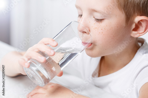 little boy in kitchen drink clean water from glass