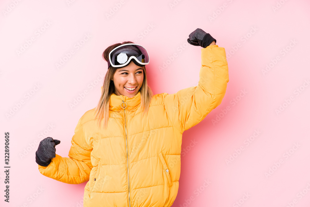 Young caucasian woman wearing a ski clothes in a pink background raising fist after a victory, winner concept. Young caucasian woman wearing a ski clothes in a pink background raising fist after a victory, winner concept.