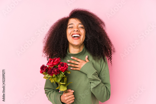 Young afro woman holding a roses isolated Young afro woman holding a roseslaughs out loudly keeping hand on chest.