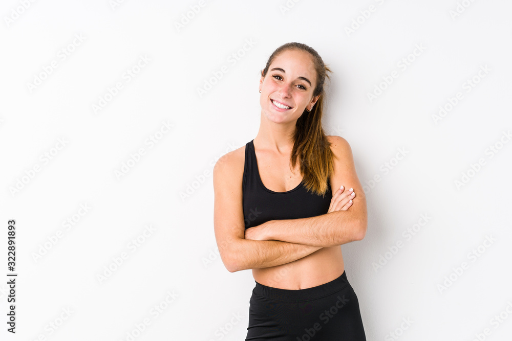 Young caucasian fitness woman posing in a white background who feels confident, crossing arms with determination. Young caucasian fitness woman posing in a white background who feels confident, crossing arms with determination.