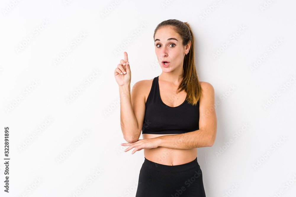 Young caucasian fitness woman posing in a white background having some great idea, concept of creativity. Young caucasian fitness woman posing in a white background having some great idea, concept of creativity.