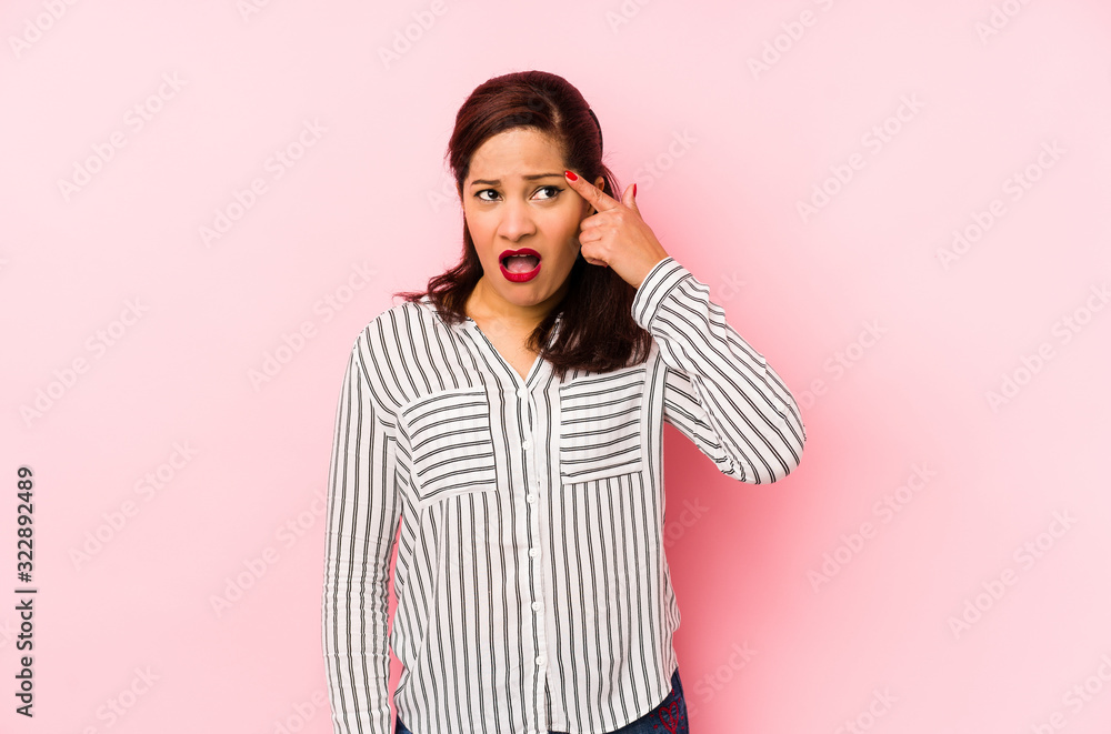 Middle age latin woman isolated on a pink background showing a disappointment gesture with forefinger. Middle age latin woman isolated on a pink background showing a disappointment gesture with forefinger.