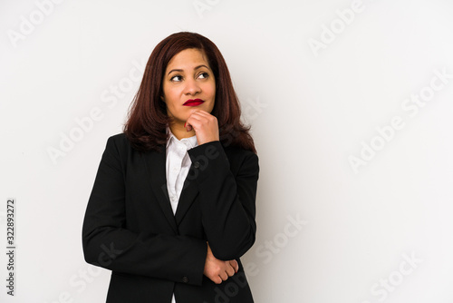 Middle age latin business woman isolated looking sideways with doubtful and skeptical expression.