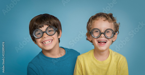 Funny happy laughing boys friends wearing silly nerd glasses isolated on blue background