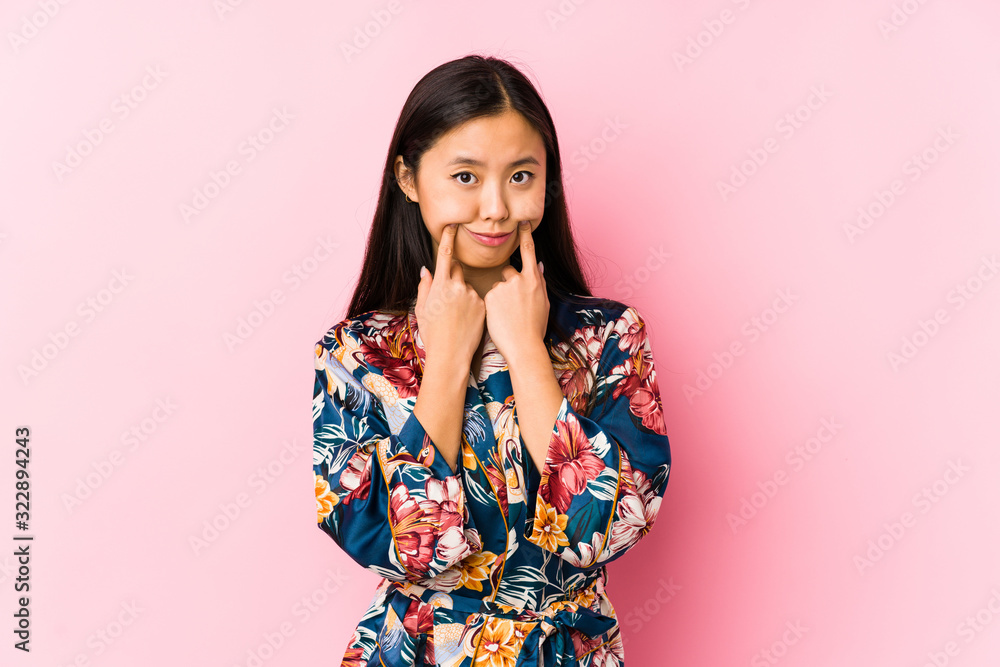 Young chinese woman wearing a kimono pajama isolated doubting between two options. Young chinese woman wearing a kimono pajama isolated doubting between two options.