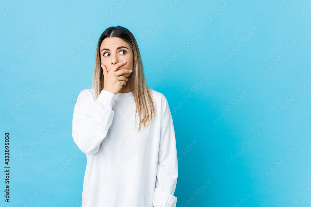 Young caucasian woman isolated thoughtful looking to a copy space covering mouth with hand. Young caucasian woman isolated thoughtful looking to a copy space covering mouth with hand.
