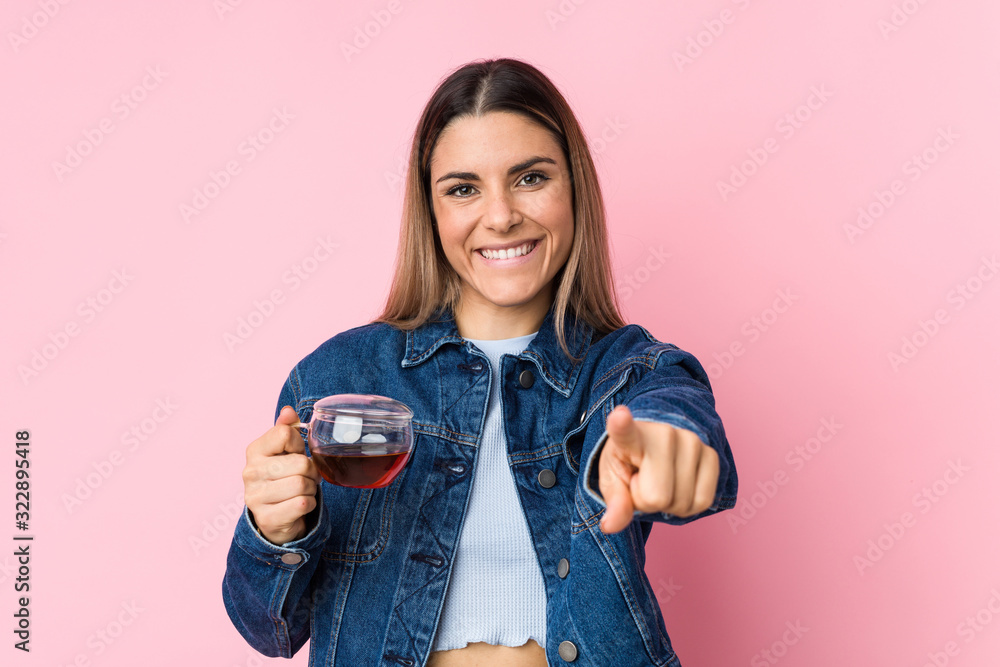 Young caucasian woman holding a tea cup cheerful smiles pointing to front. Young caucasian woman holding a tea cup cheerful smiles pointing to front.