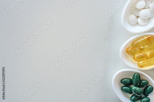 Top view of natural vitamin supplement on white spoon as frame of marble texture background. Healthy eating lifestyle trend concept.