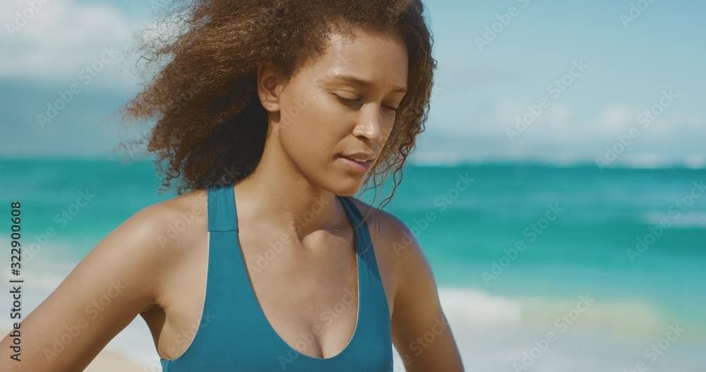 Portrait of a young serious african american woman looking down, young black woman resting after her beach workout Portrait of a young serious african american woman looking down, young black woman resting after her beach workout