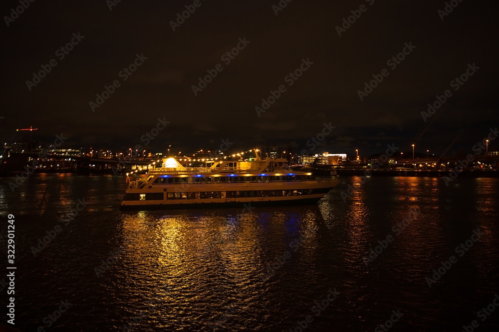 Night pleasure boat, or yacht for a walk with people. Night city with a river and a big boat