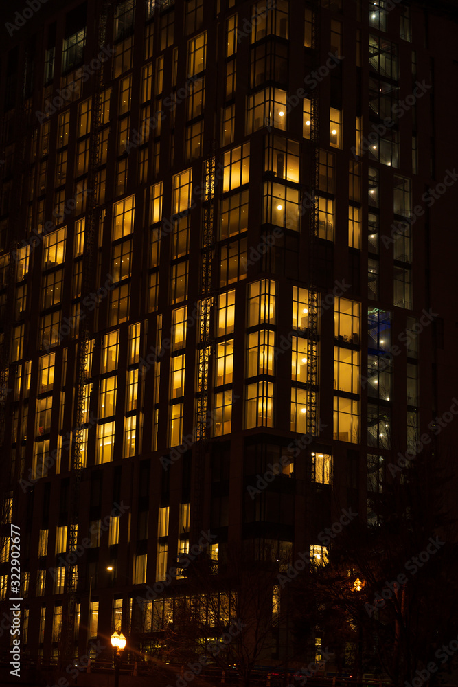 Obraz premium Night skyscraper close up, glowing window. Night work.Vertical shot.