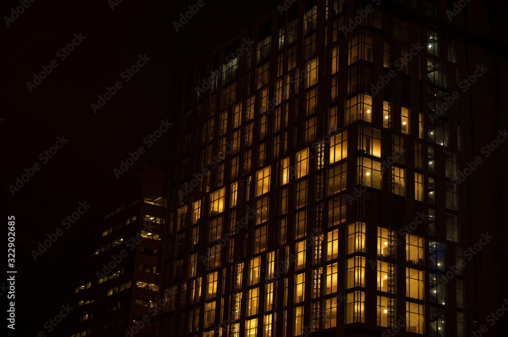 Obraz premium Night skyscraper close up, glowing window. Night work.Horizontal frame.