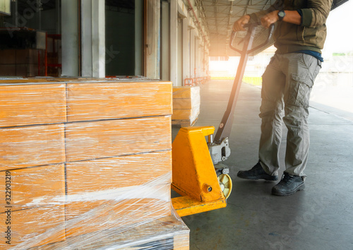 Workers Courier Using Hand Pallet Jack Unloading Package Boxes into Cargo Container. Delivery Shipment Boxes. Trucks Loading at Dock Warehouse. Supply Chain. Warehouse Shipping Transport Logistics.	