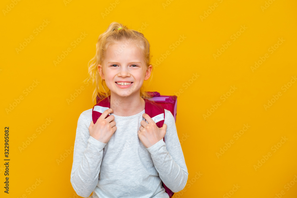 Back to school. Portrait of blonde caucasian school girl with bag on yellow studio background. Education. looking and smiling at camera Back to school. Portrait of blonde caucasian school girl with bag on yellow studio background. Education. looking and smiling at camera