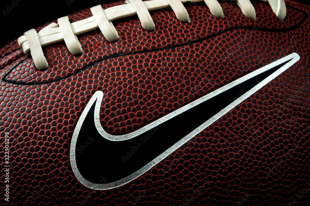 London, UK - 12th January 2018:Illustrative editorial of a macro image of a  american football ball with visible laces, stitches, pigskin pattern and  the nike logo with dramatic lighting Stock Photo