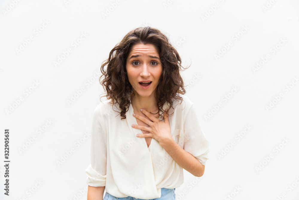 Pleasantly surprised woman looking at camera. Beautiful curly lady holding hand on chest. Surprised concept Pleasantly surprised woman looking at camera. Beautiful curly lady holding hand on chest. Surprised concept