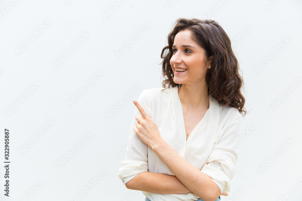 Beautiful smiling woman pointing with finger. Cheerful curly lady looking aside. Direction concept Beautiful smiling woman pointing with finger. Cheerful curly lady looking aside. Direction concept