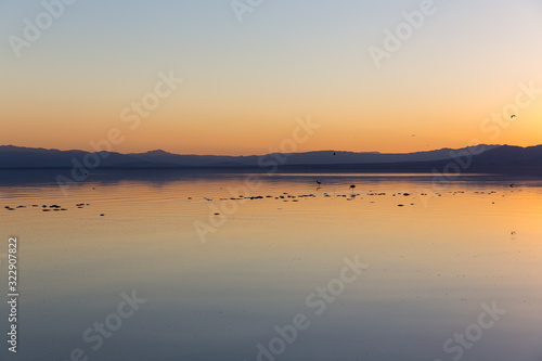Fototapeta Naklejka Na Ścianę i Meble -  Orange sunset with birds on lake at Salton Sea, California