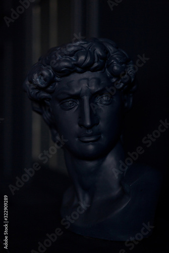 Gypsum copy of ancient statue Apollo head in trend classic blue color. Plaster sculpture man face