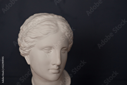 Gypsum copy of ancient statue Venus head on dark blue background. Plaster sculpture woman face.