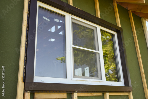Wall covering of the frame house with panels of vinyl siding. construction or reconstruction, repair of the house. Installation of plastic Windows in a new residential building.
