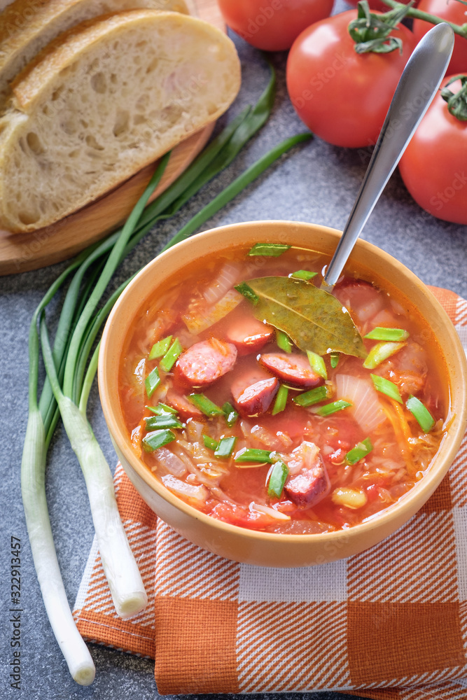 Tomato soup with smoked sausages, bread, green onion, tomatoes and kitchen towel Tomato soup with smoked sausages, bread, green onion, tomatoes and kitchen towel