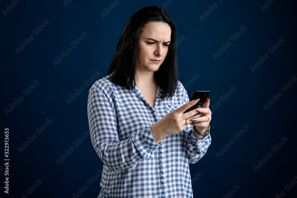 Beautiful woman dressed casually thinks of the message and looks surprised at the phone Beautiful woman dressed casually thinks of the message and looks surprised at the phone
