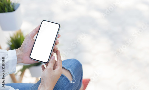 Mockup image blank white screen cell phone.woman hand holding texting using mobile sitting at coffee shop.background empty space for advertise text.people contact marketing business,technology