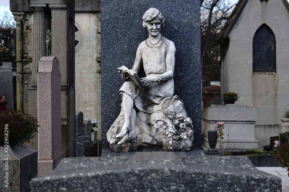 Tombstone with a sculpture of a reading girl in the famous Paris Cemetery of Lachaise