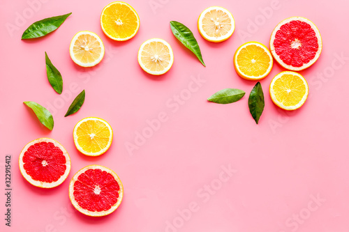 Fototapeta Naklejka Na Ścianę i Meble -  Citrus slices frame - lemons, grapefruits, leaves - on pink background top-down copy space