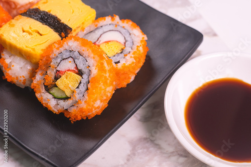 Sushi Roll with salmon, sushi maki roll and tamago sushi on black plate